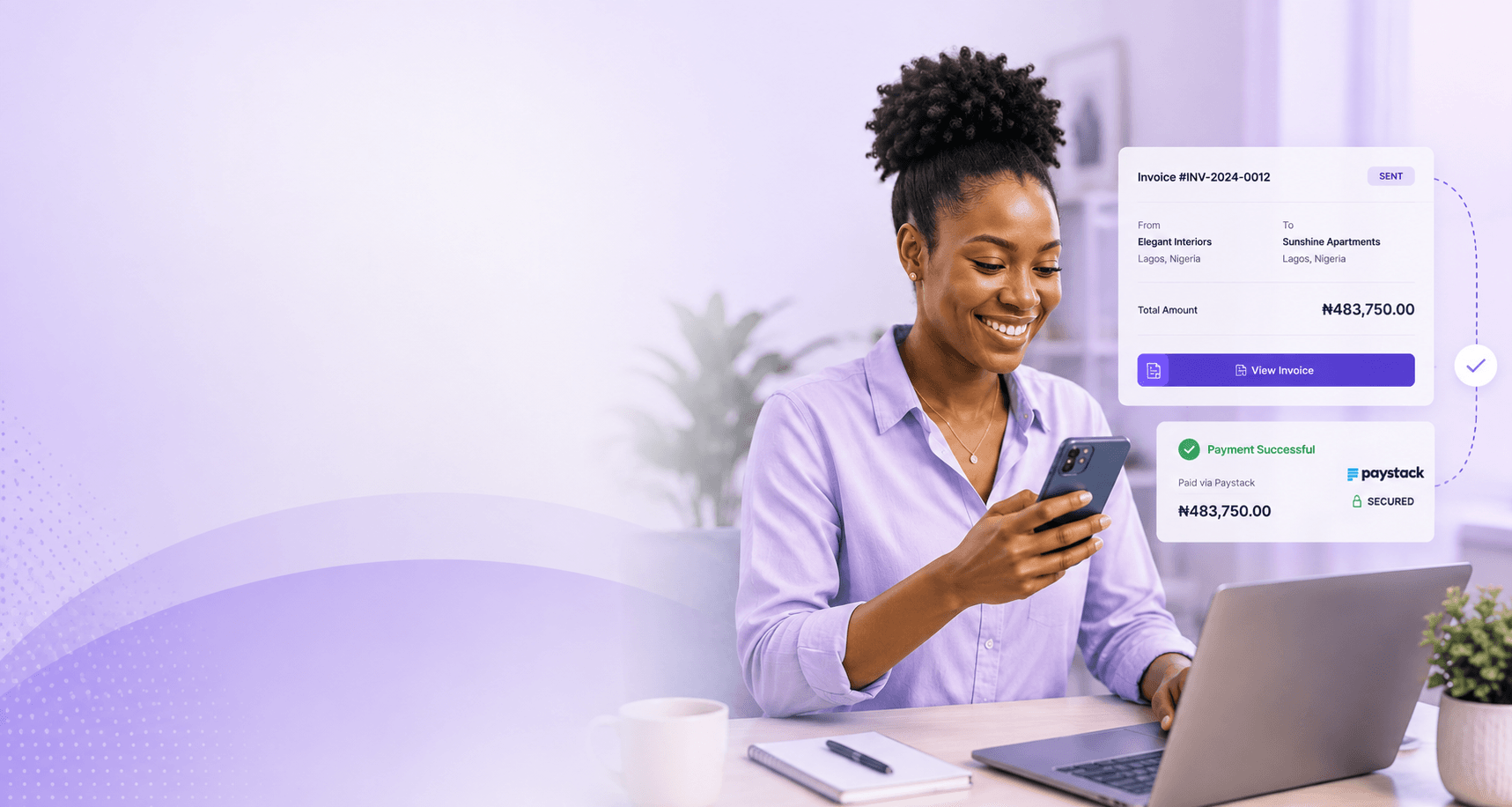 A business owner checking a payment on a phone beside a laptop